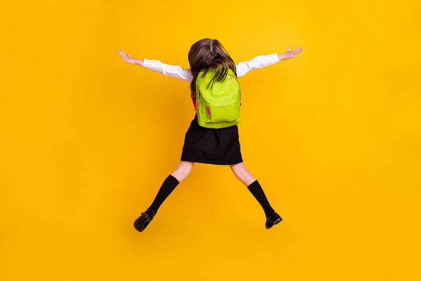 Back rear spine side view photo of small schoolgirl jump up wear backpacki solated on yellow color background - Fotografie, Obrázek