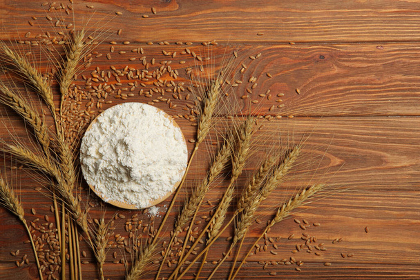 Wheat flour and spikelets of wheat on a light background - Foto, afbeelding