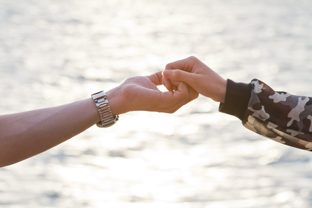 Nuori pari rakastunut kädestä katsoen auringonlaskuun
 - Valokuva, kuva