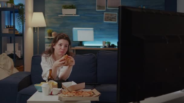Osoba jedząca pyszne hamburgery i frytki w salonie - Materiał filmowy, wideo