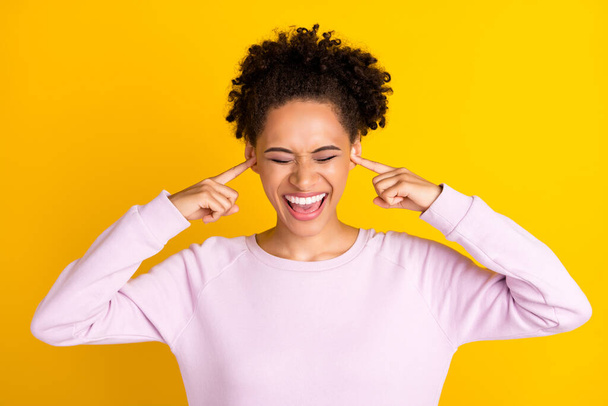Photo of pretty dark skin people closed eyes fingers in ears open mouth isolated on yellow color background - Foto, Imagen