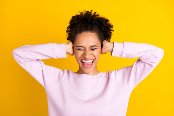 Foto de una joven infeliz afro-americana enojada sosteniendo las manos tapadera oídos ruido fuerte aislado sobre fondo de color amarillo - Foto, Imagen