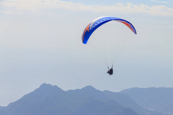 Paralotniarze lecący ze szczytu góry Tahtali koło Kemer, prowincja Antalya w Turcji. Pojęcie aktywnego stylu życia i ekstremalnej przygody sportowej - Zdjęcie, obraz