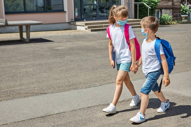 A girl and a boy, brother and sister go to school for lessons, classes in protective masks. Back to school after vacation. The new school year - Fotoğraf, Görsel