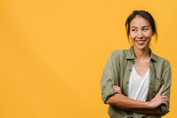 Portrait of young Asia lady with positive expression, arm crossed, smile broadly, dressed in casual cloth over yellow background. Happy adorable glad woman rejoices success. Facial expression concept. - Foto, Imagen