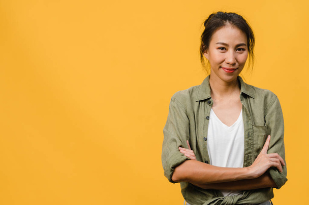 Portrait of young Asia lady with positive expression, arms crossed, smile broadly, dressed in casual clothing and looking at camera over yellow background. Happy adorable glad woman rejoices success. - Foto, imagen