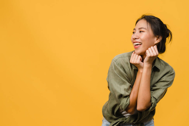 Retrato de una joven asiática con expresión positiva, sonrisa amplia, vestida con ropa casual sobre fondo amarillo. Feliz adorable mujer feliz regocija el éxito. Concepto de expresión facial. - Foto, imagen