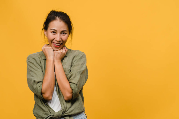 Young Asia lady with positive expression, smile broadly, dressed in casual clothing and looking at camera over yellow background. Happy adorable glad woman rejoices success. Facial expression concept. - Fotó, kép