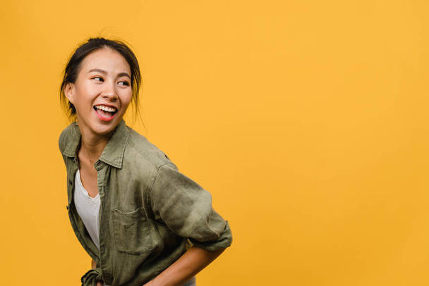Portrait of young Asia lady with positive expression, smile broadly, dressed in casual clothing over yellow background. Happy adorable glad woman rejoices success. Facial expression concept. - Фото, изображение
