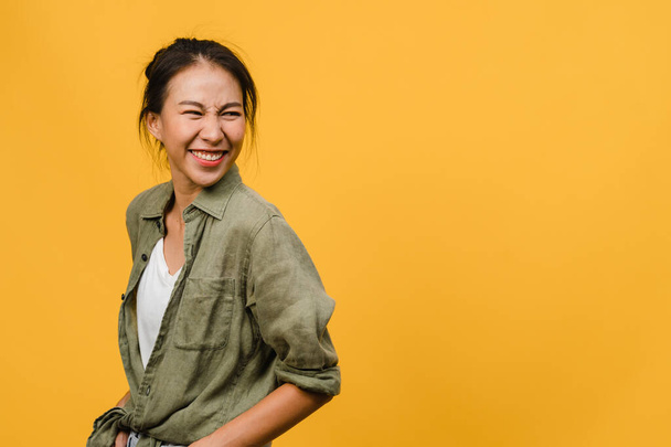 肯定的な表現、笑顔を広く、黄色の背景にカジュアルな服を着て若いアジアの女性の肖像画。幸せな愛らしい幸せな女性は成功を喜びます.表情コンセプト. - 写真・画像