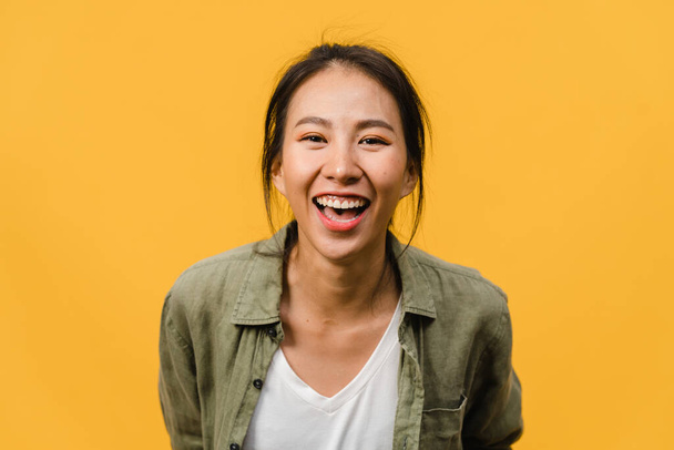 Fiatal ázsiai hölgy pozitív arckifejezéssel, széles mosollyal, alkalmi ruhába öltözve, és a kamerát sárga háttérrel. Boldog imádnivaló boldog nő örül a sikernek. Az arckifejezés fogalma. - Fotó, kép