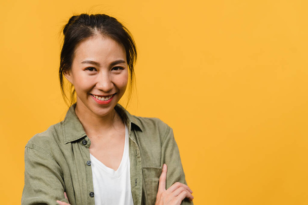 A fiatal ázsiai hölgy portréja pozitív arckifejezéssel, keresztbe tett karokkal, széles mosollyal, alkalmi ruhába öltözve és sárga háttérrel a kamerába nézve. Boldog imádnivaló boldog nő örül a sikernek. - Fotó, kép