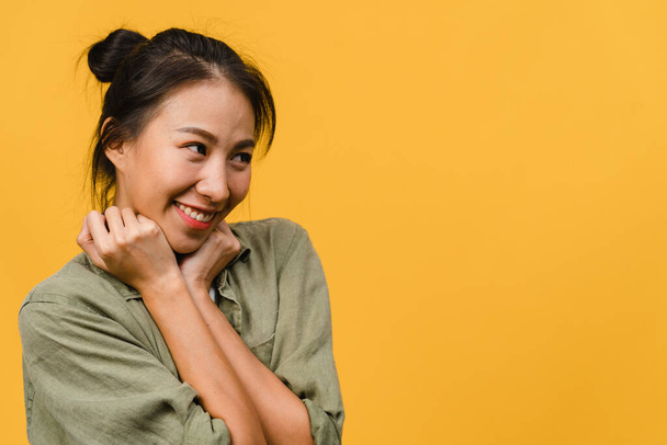 Portret van jonge Aziatische dame met positieve uitdrukking, brede glimlach, gekleed in casual kleding over gele achtergrond. Gelukkige schattige blije vrouw verheugt zich succes. Gezichtsuitdrukking. - Foto, afbeelding