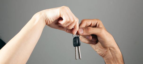 couple holding house keys on gray background - Foto, Bild