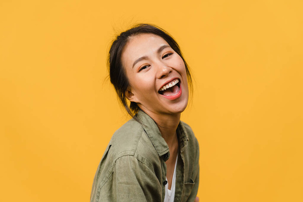 肯定的な表情で若いアジアの女性は、笑顔を広く、カジュアルな服を着て、黄色の背景にカメラを見て。幸せな愛らしい幸せな女性は成功を喜びます.表情コンセプト. - 写真・画像