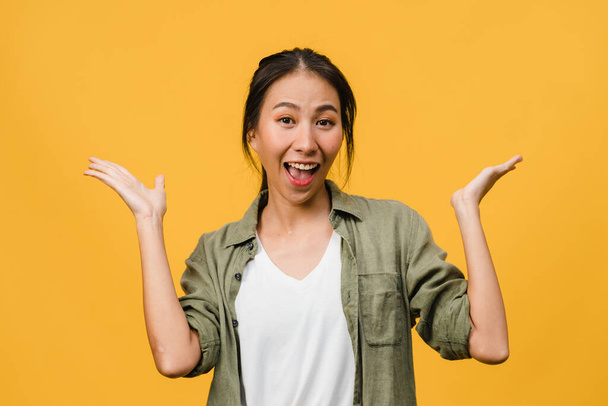 Young Asia lady feel happiness with positive expression, joyful surprise funky, dressed in casual cloth and looking at camera isolated on yellow background. Happy adorable glad woman rejoices success. - Photo, Image