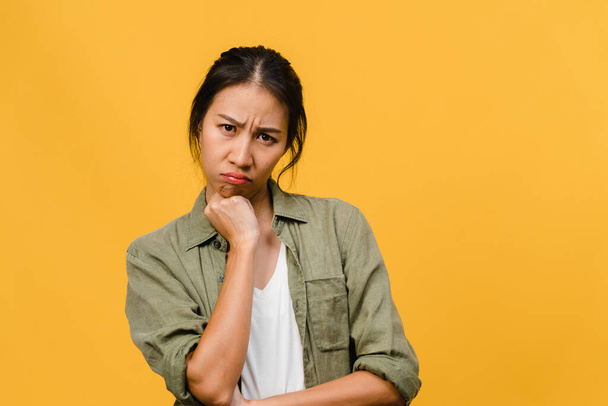 Young Asia lady with negative expression, excited screaming, crying emotional angry in casual clothing and look at camera isolated on yellow background with blank copy space. Facial expression concept - Photo, Image