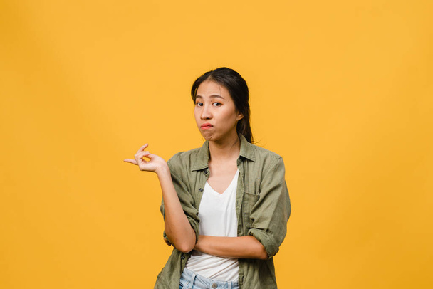 Young Asia Lady shows something amazing at blank space with negative expression, excited screaming, crying emotional angry looking at camera isolated over yellow background. Facial expression concept. - Fotó, kép