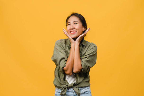 Portrait of young Asia lady with positive expression, smile broadly, dressed in casual clothing over yellow background. Happy adorable glad woman rejoices success. Facial expression concept. - Foto, Imagen