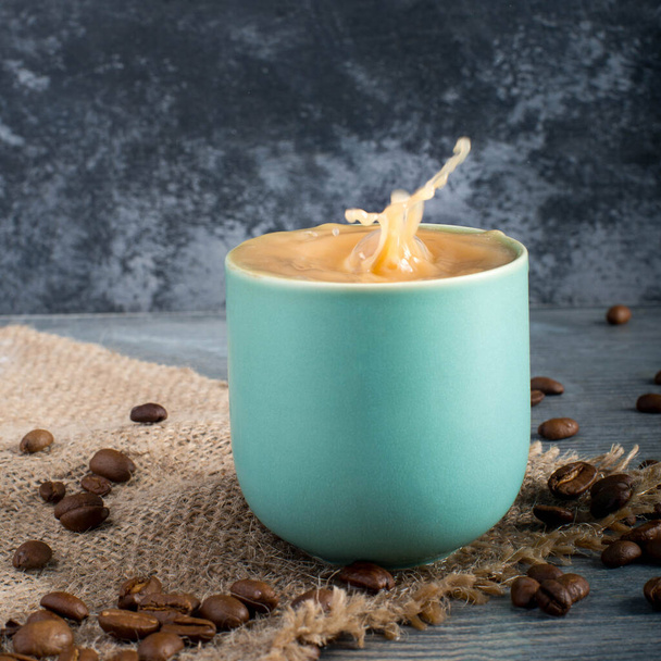 Брызги кофе, чашки синего цвета, жареные бобы, текстурированный фон - Фото, изображение