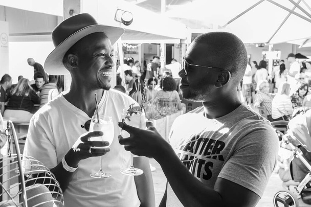 JOHANNESBURG, SOUTH AFRICA - Jan 05, 2021: A shallow focus of African male friends drinking and generally enjoying a day out at a Food and Wine Fair - Фото, изображение