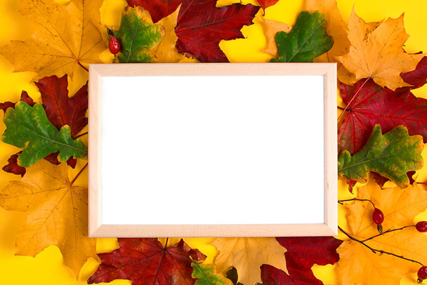 Empty wooden frame mock up and autumn leaves on yellow background. Template for design. Copy space. - Photo, Image