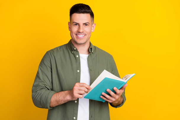Photo portrait man smiling keeping book reading novel isolated vibrant yellow color background - Fotó, kép