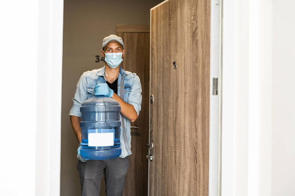 Delivery water man wear protective face medical mask during coronavirus pandemia - Foto, imagen