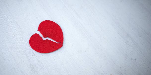 Ein gebrochenes Herz ist rot auf weißem Hintergrund. Abbruch der Beziehungen. Das Ende der Liebe. - Foto, Bild