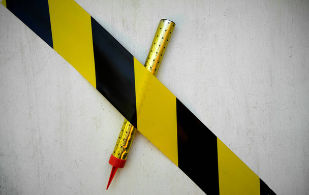 Um foguete de cor dourada é coberto com um filme amarelo proibindo em um fundo branco, o lançamento de fogos de artifício é proibido. - Foto, Imagem