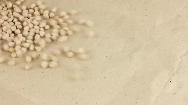grão de bico seco espalha no papel artesanal, mãos humanas recolhe-los, close-up vista, proteína vegetal para vegan, ingrediente para o húmus - Filmagem, Vídeo