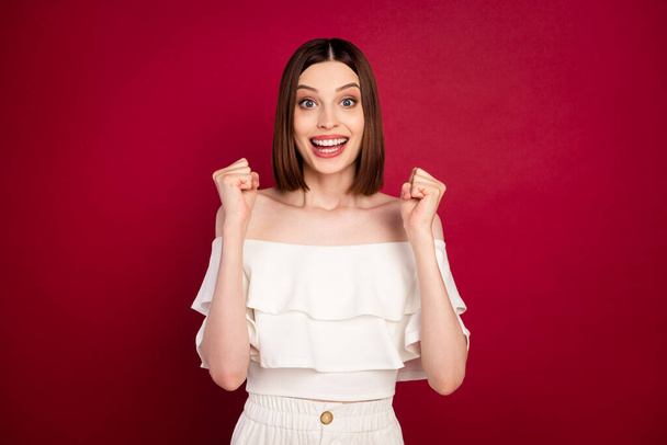 Photo of hooray brown hairdo millennial lady hands fists wear white bare shoulders top isolated on red color background - Foto, Imagem