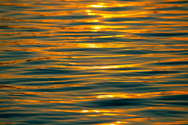 Reflection of the setting sun in a wave of water. Natural background texture - Zdjęcie, obraz