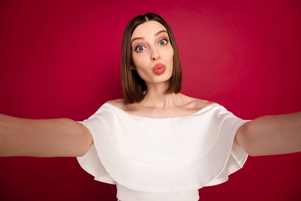 Photo of young attractive girl pouted lips send air kiss make selfie isolated over red color background - Foto, imagen