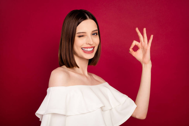 Profile side photo of young girl happy positive smile show okay alright sign win eye isolated over red color background - Foto, Imagen