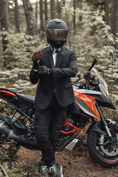Uomo d'affari motociclista con guanti e casco in posa nella foresta - Foto, immagini