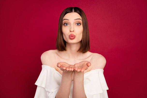 Photo of flirty brown hairdo young lady blow kiss wear white naked shoulders blouse isolated on red color background - Zdjęcie, obraz