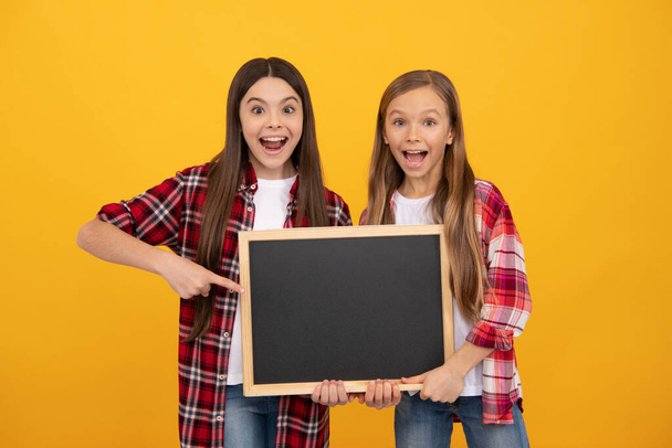 užaslé teen dívky v kostkované ukazující prstem na školní tabuli pro kopírování prostoru, reklama. - Fotografie, Obrázek