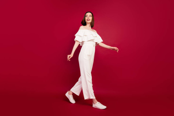 Full body profile side photo of young attractive woman happy positive smile go walk step isolated over red color background - Fotó, kép