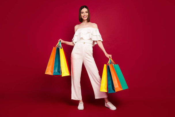 Full size photo of cool brown hairdo millennial lady with bags wear top pants isolated on red background - Φωτογραφία, εικόνα