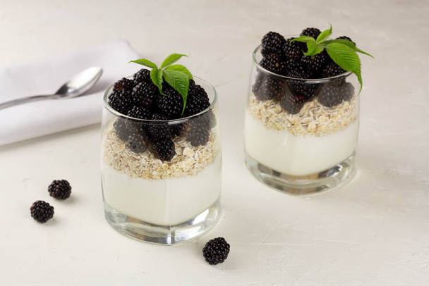 Granola with yoghurt and fresh blackberry in glasses on light background - Photo, Image