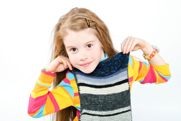 Studio shot of pretty little girl trying on knitted scarf - 写真・画像