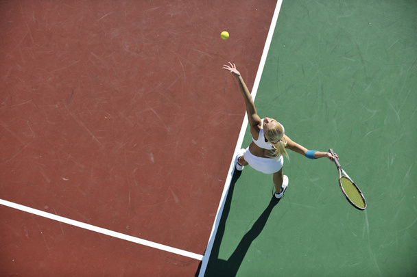 Young fit woman play tennis outdoor on orange tennis field at early morning - Foto, Imagen