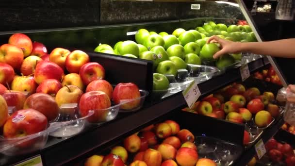 Frau wählt frische grüne Äpfel im Lebensmittelgeschäft aus. - Filmmaterial, Video