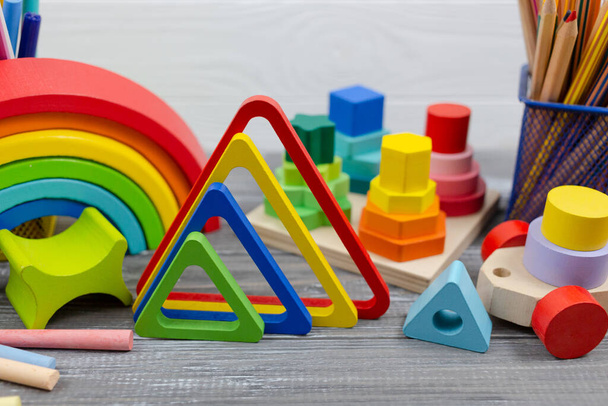 Multicolored Wooden rainbow toy, sorter, pencils, blocks on wooden table. Back to school, games for kindergarten, preschool education. - Photo, Image
