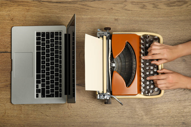 Woman using old typewriter near laptop at wooden table, top view. Concept of technology progress - Foto, Bild