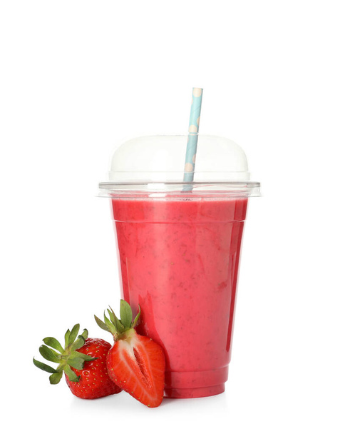 Delicious smoothie with straw in plastic cup and fresh strawberries on white background - Fotó, kép