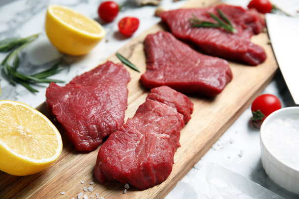 Fresh raw meat steaks and spices on white marble table, closeup - Photo, Image
