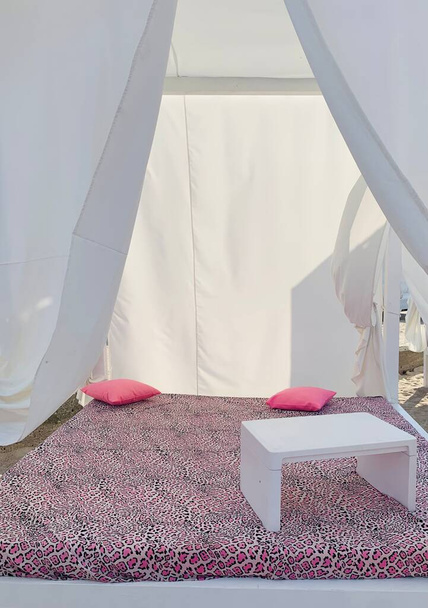 Cazibeli sahil şezlongları güneşli yatak, masa, yastıklar ve örtü. - Fotoğraf, Görsel