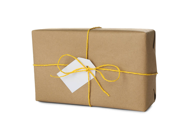 Parcel wrapped in kraft paper with tag on white background - Fotó, kép